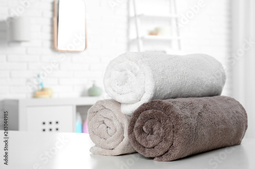 Rolled fresh towels on table in bathroom. Space for text