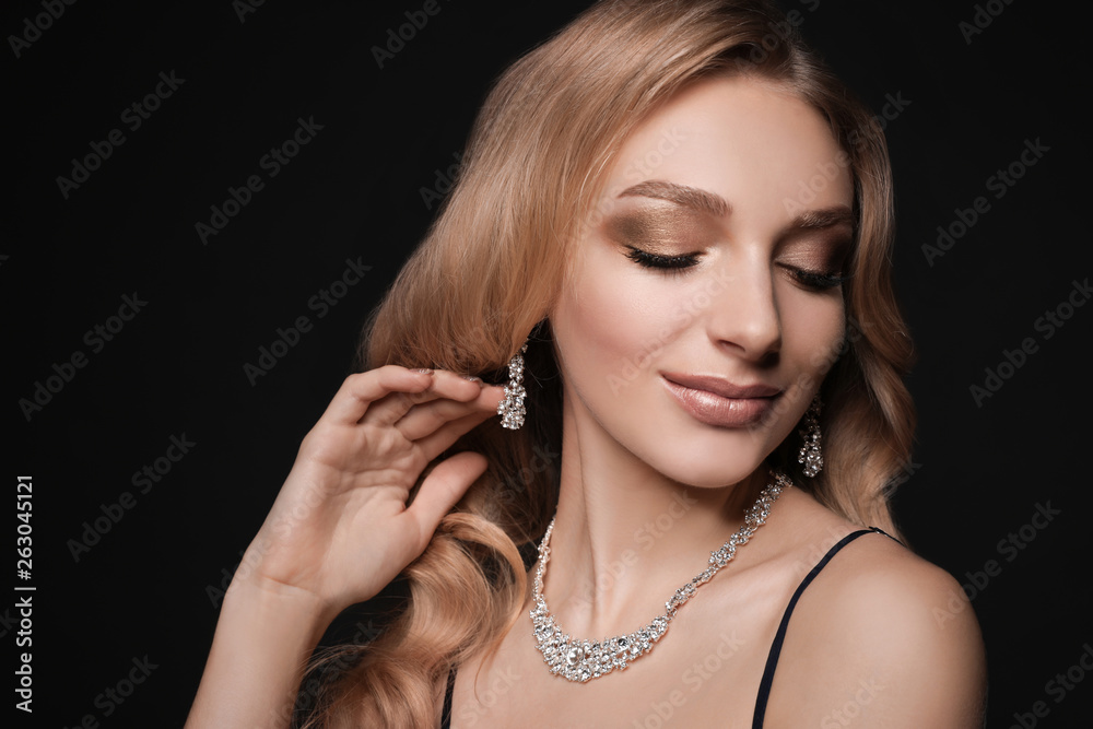 Obraz premium Beautiful young woman with elegant jewelry on dark background