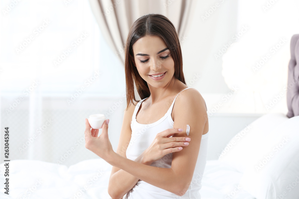 Young woman with perfect smooth skin applying cream in bedroom. Beauty and body care Young woman with perfect smooth skin applying cream in bedroom. Beauty and body care