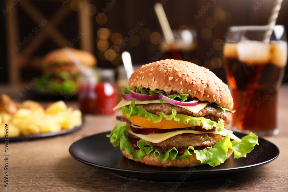 Plate with delicious hamburger on wooden table. Space for text Plate with delicious hamburger on wooden table. Space for text