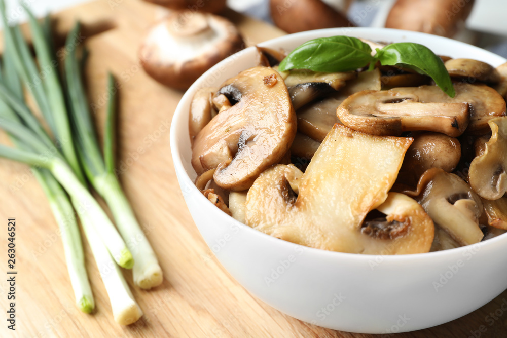 Delicious cooked mushrooms with basil in bowl on table, closeup. Space for text Delicious cooked mushrooms with basil in bowl on table, closeup. Space for text