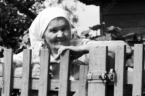 Black and white Grandma smiles near a fence, summer