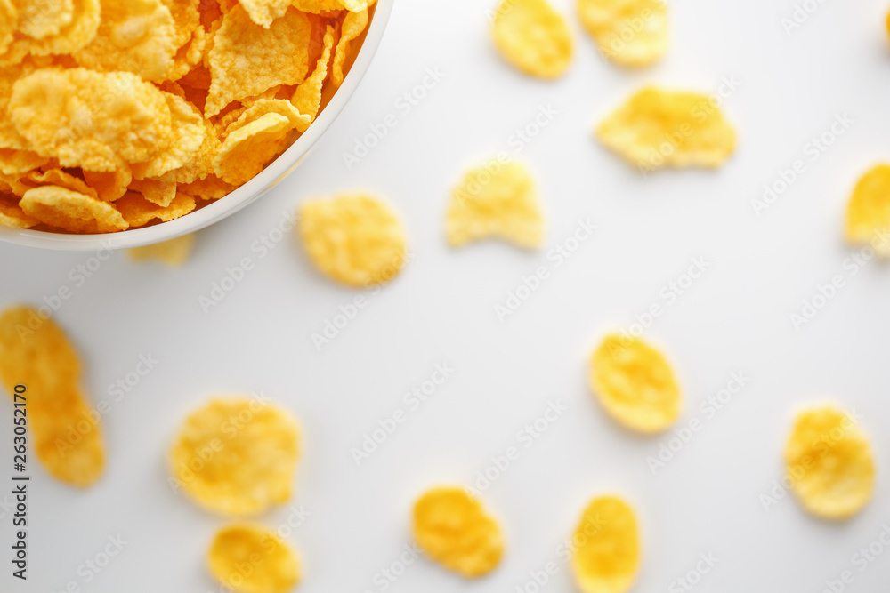 White cup with golden corn flakes, isolated on white background. Hopya crumbled around the cup. View from above White cup with golden corn flakes, isolated on white background. Hopya crumbled around the cup. View from above