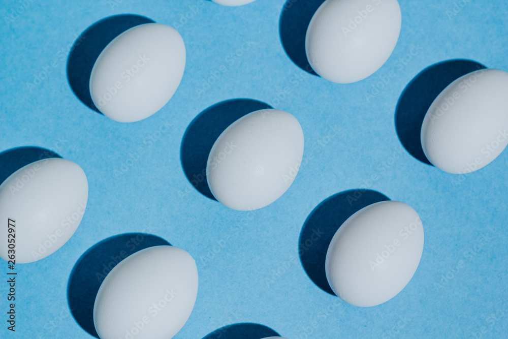 White chicken eggs with empty space, on a blue background. Abstract image White chicken eggs with empty space, on a blue background. Abstract image
