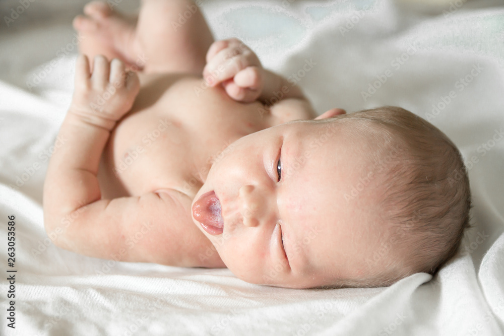 Closeup portrait of cute newborn baby lying down in the bed at home, smiling face, happy childhood, new life concept Closeup portrait of cute newborn baby lying down in the bed at home, smiling face, happy childhood, new life concept