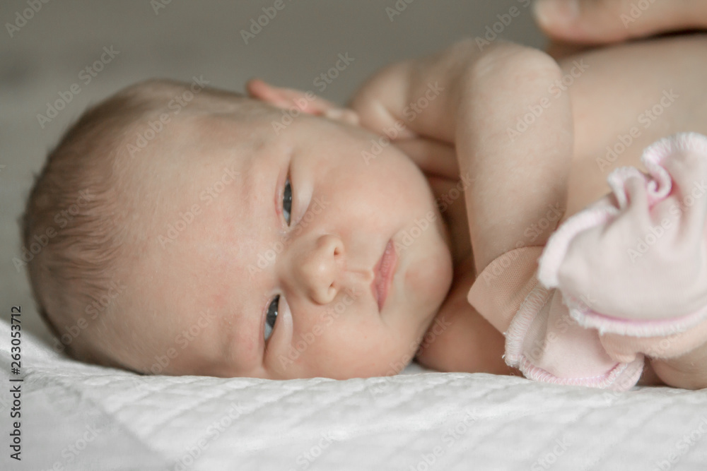 Closeup portrait of cute newborn baby lying down in the bed at home, smiling face, happy childhood, new life concept Closeup portrait of cute newborn baby lying down in the bed at home, smiling face, happy childhood, new life concept