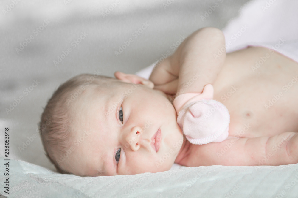 Closeup portrait of cute newborn baby lying down in the bed at home, smiling face, happy childhood, new life concept Closeup portrait of cute newborn baby lying down in the bed at home, smiling face, happy childhood, new life concept