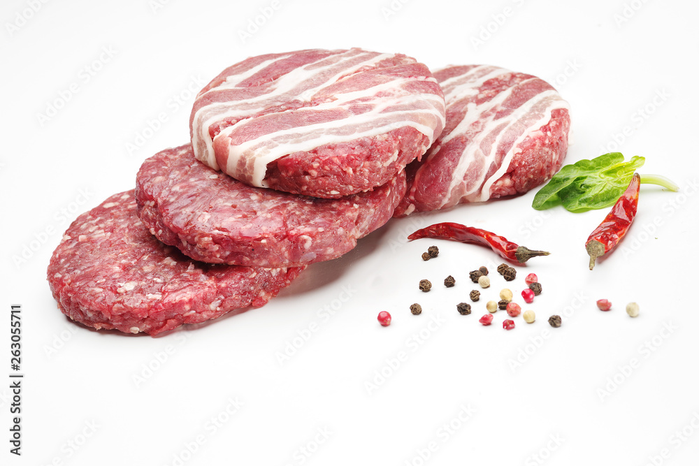 Raw meat patties with spices for burgers on a white background. Raw meat patties with spices for burgers on a white background.