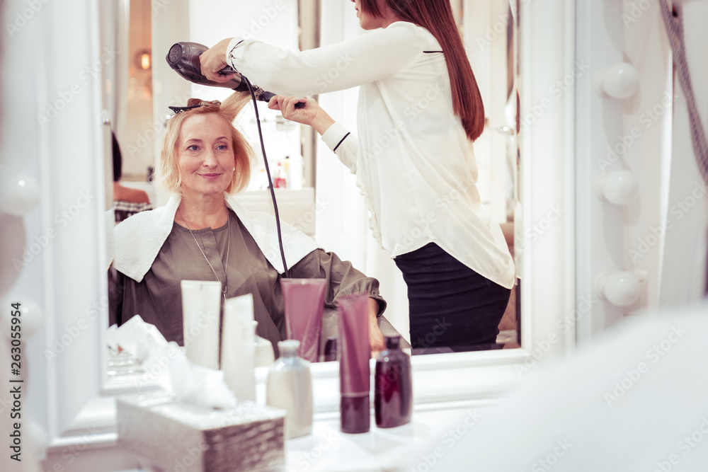 Cheerful elderly blonde woman looking at her reflection Cheerful elderly blonde woman looking at her reflection