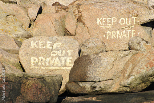 Keep Out Sign Painted on Boulders at the Seashore