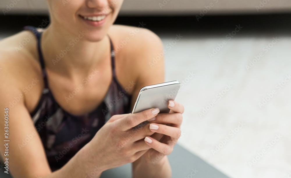 Woman using fitness app on her smartphone after workout Woman using fitness app on her smartphone after workout