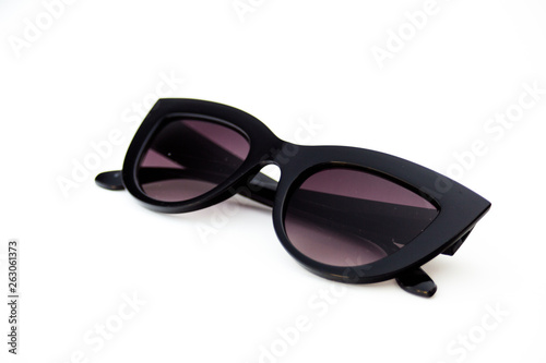 Black colored thick frame sunglasses laying on a white background. earpiece parts are folded.