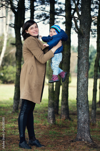 happy mother holding her little son in her arms in the park. girl and little boy in the forest. © alas_spb