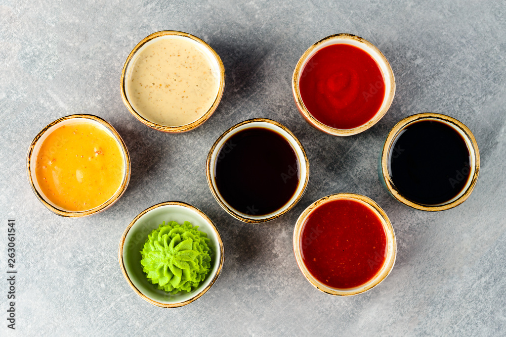 Different tasty sauces in bowls on grey background Different tasty sauces in bowls on grey background
