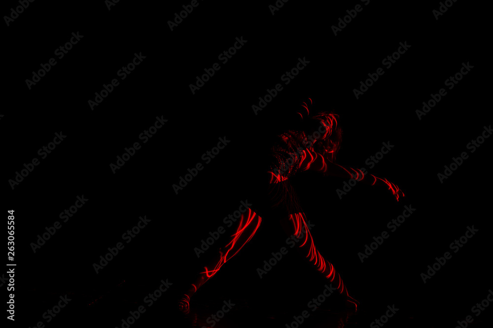 Ballet dancer dancing in front of and red light while expressing the hell with her magnificent dance moves. long exposure motion blur Ballet dancer dancing in front of and red light while expressing the hell with her magnificent dance moves. long exposure motion blur
