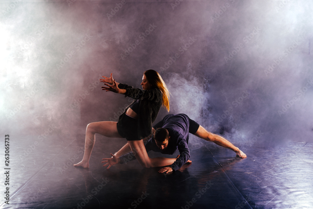 Modern dance couple twisting their legs and lening close to the ground, touching and combining their bodies in extremely unique modern dance experience.