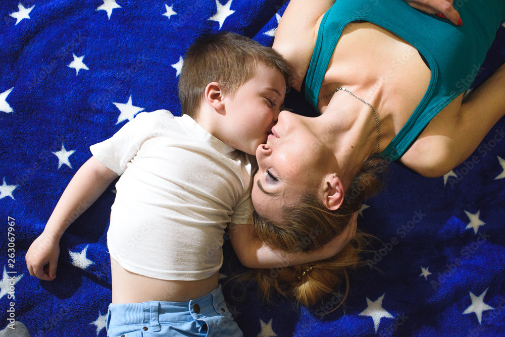 Fototapeta premium Happy mom and son are lying and looking at each other