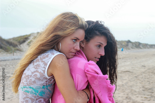 Two cute funny young girls are walking along the beach  laughing  having fun  crazy emotions  with bikini