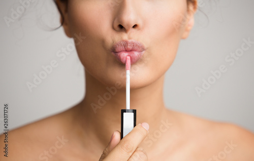 Obraz na płótnie Young woman applying lip gloss on her lips