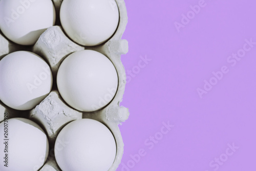 White chicken eggs in a cardboard package with empty space  on a blue background