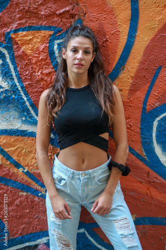 Trendy beautiful long haired young model posing on graffiti background