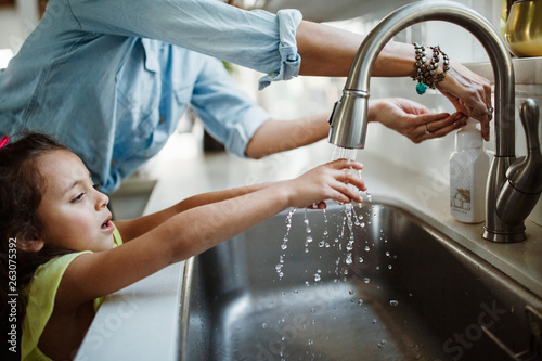 Fényképezés Midsection of mother with daughter washing hands in sink at home
