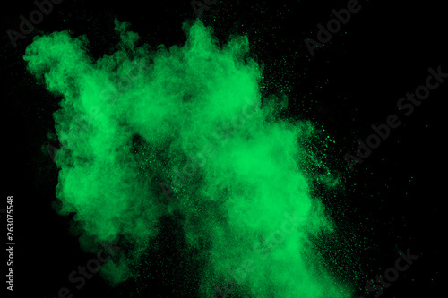 Green color powder explosion cloud on black background.Green dust splash on dark background.