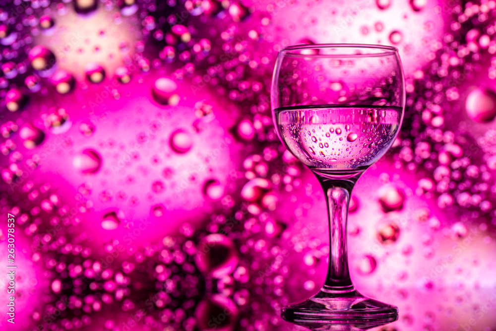 ransparent glasses with water and oily drops on colorful background ransparent glasses with water and oily drops on colorful background
