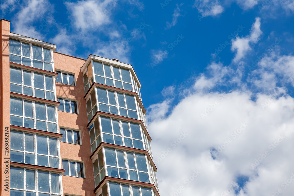 New modern apartment house on a background of blue cloudy sky at sunny day. Real estate concept. New modern apartment house on a background of blue cloudy sky at sunny day. Real estate concept.