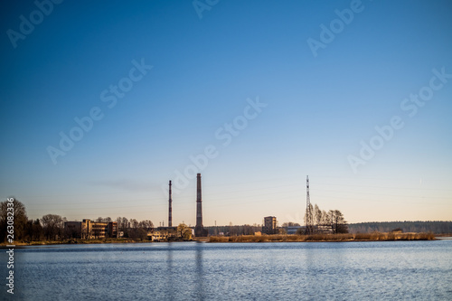 Old factory on a river bank with a blue sky isolated