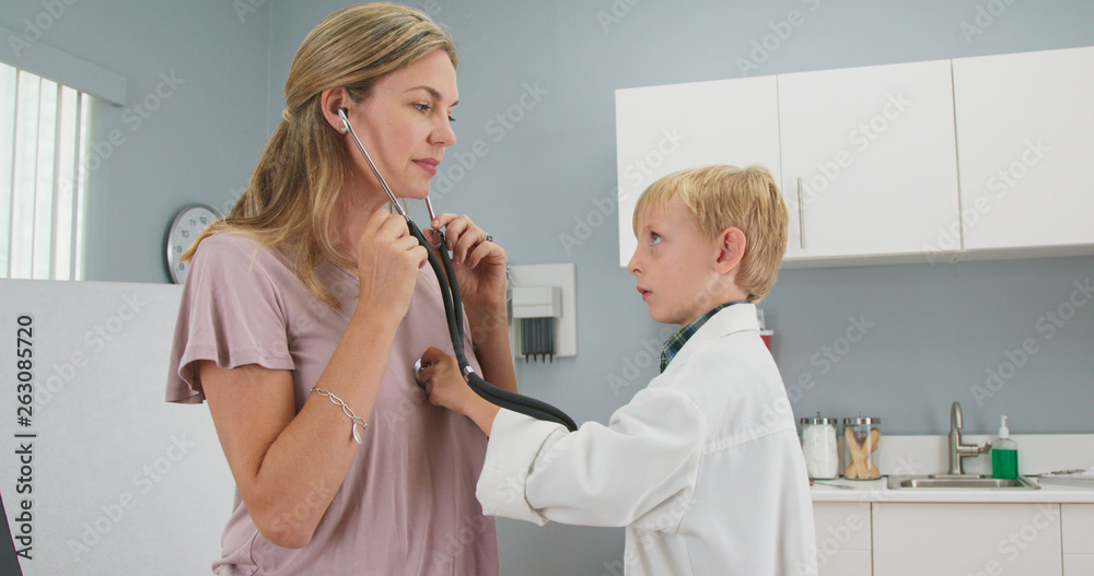 Cute child pretending to be a doctor with his mother while in
