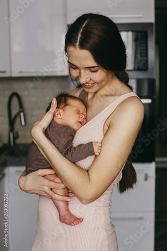 Young mother, holding tenderly her newborn baby girl, close portrait