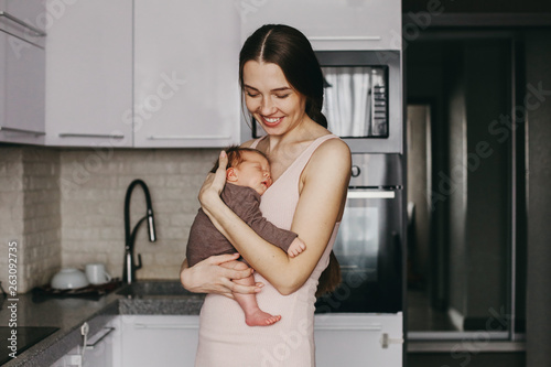 Young mother, holding tenderly her newborn baby girl, close portrait
