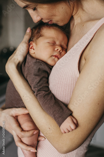 Young mother, holding tenderly her newborn baby girl, close portrait photo