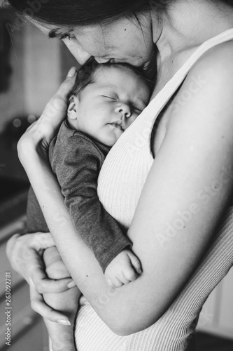 Young mother, holding tenderly her newborn baby girl, close portrait