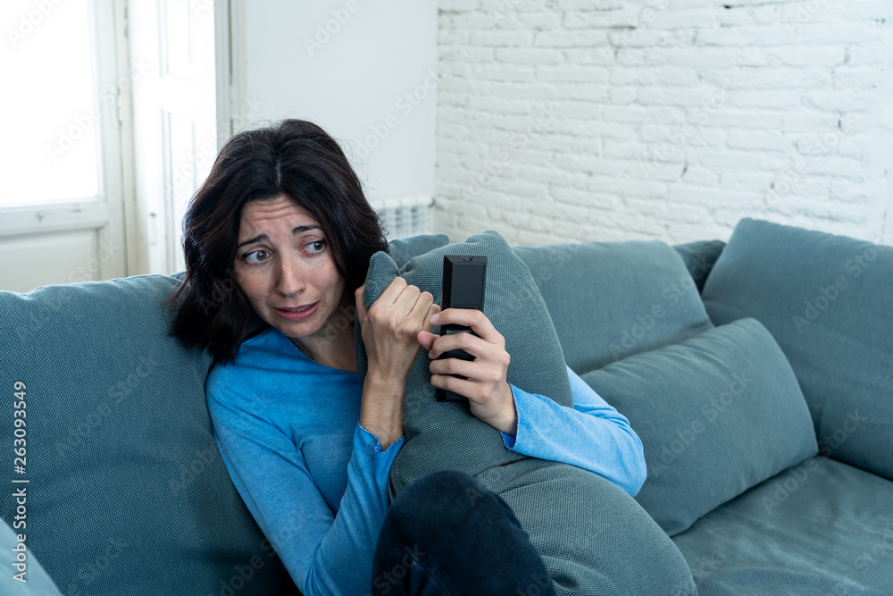 Portrait of a young woman looking scared and shocked watching scary movie on TV. Portrait of a young woman looking scared and shocked watching scary movie on TV.