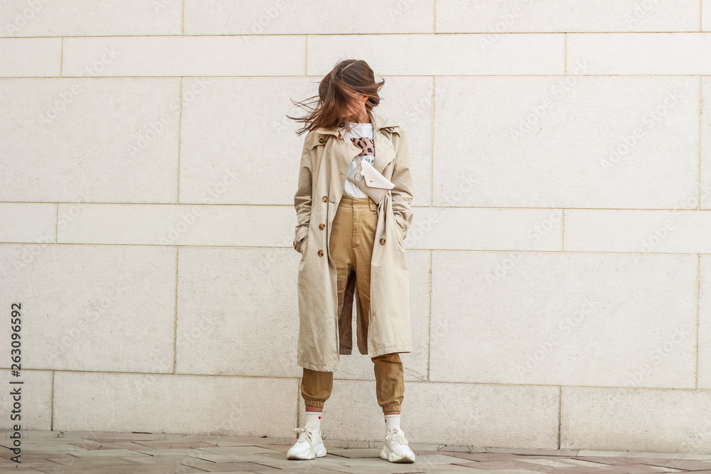Portrait shooting of a stylish girl. Beige shades. Trends of spring and summer 2019. Pants of cork.Trench cloak, a wide jacket. - obrazy, fototapety, plakaty 