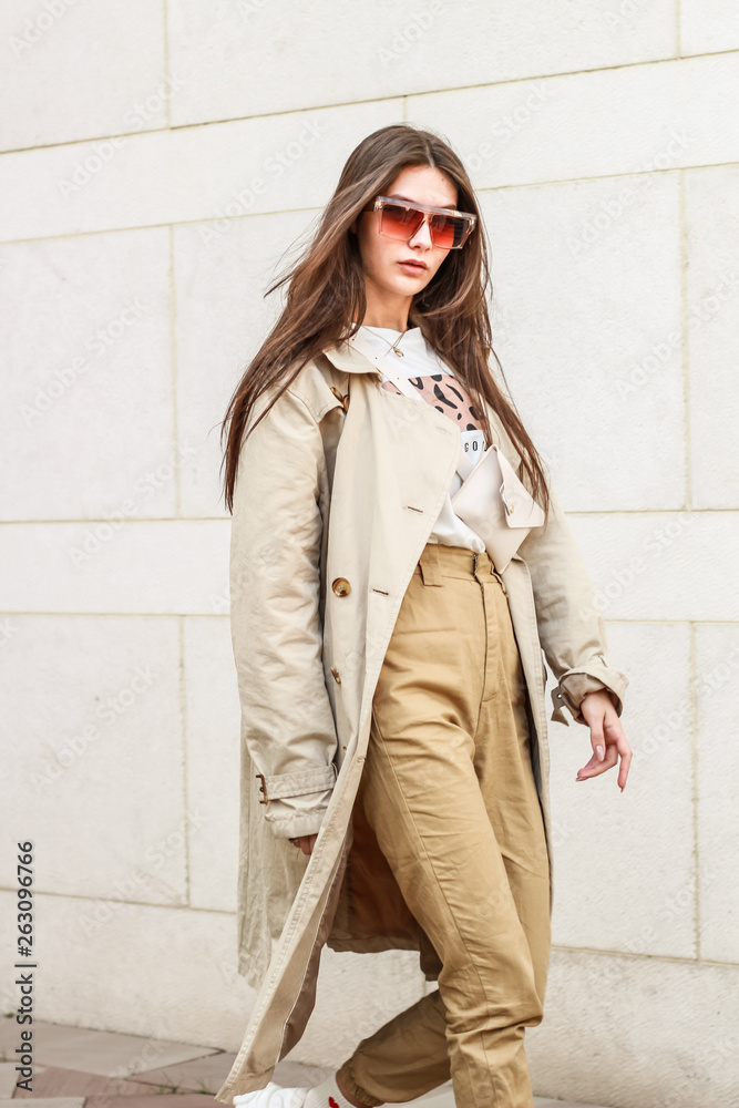 Portrait shooting of a stylish girl. Beige shades. Trends of spring and summer 2019. Pants of cork.Trench cloak, a wide jacket. Portrait shooting of a stylish girl. Beige shades. Trends of spring and summer 2019. Pants of cork.Trench cloak, a wide jacket.