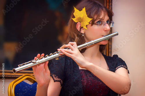Fototapeta The girl plays a large silver transverse flute