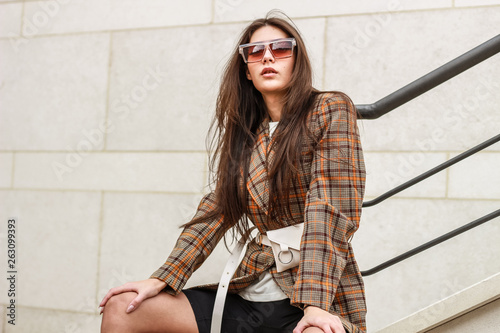 Portrait shooting of a stylish girl. Beige shades. Trends of spring and summer 2019. Wide jacket and belt leather bag. White sneakers and bike shorts