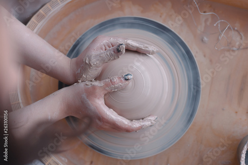 Potter at work. Top view of potter making ceramic pot on the pottery wheel. Gentle female hands.