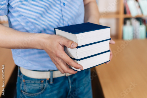 Male hands holding a stack of books. © Svyatoslav Balan