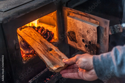 Man putting log to wood burning stove photo