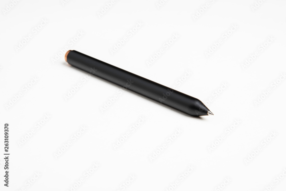 An extreme close-up or macro shot of a minimalist black barrel ballpoint pen with selective focus on tip set against plain white background. An extreme close-up or macro shot of a minimalist black barrel ballpoint pen with selective focus on tip set against plain white background.