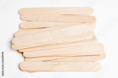 A set of plain and unused wooden crafts sticks strewn artfully on a white background.