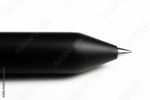A macro shot of a minimalist barrel ballpoint pen with selective focus on the writing tip set on a plain white background.