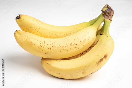 A close-up product studio shot of a naturally overripe bunch of yellow bananas set on a plain white background.