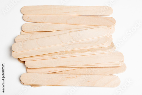 A set of plain, unused wide wooden craft sticks strewn artfully on a white background.