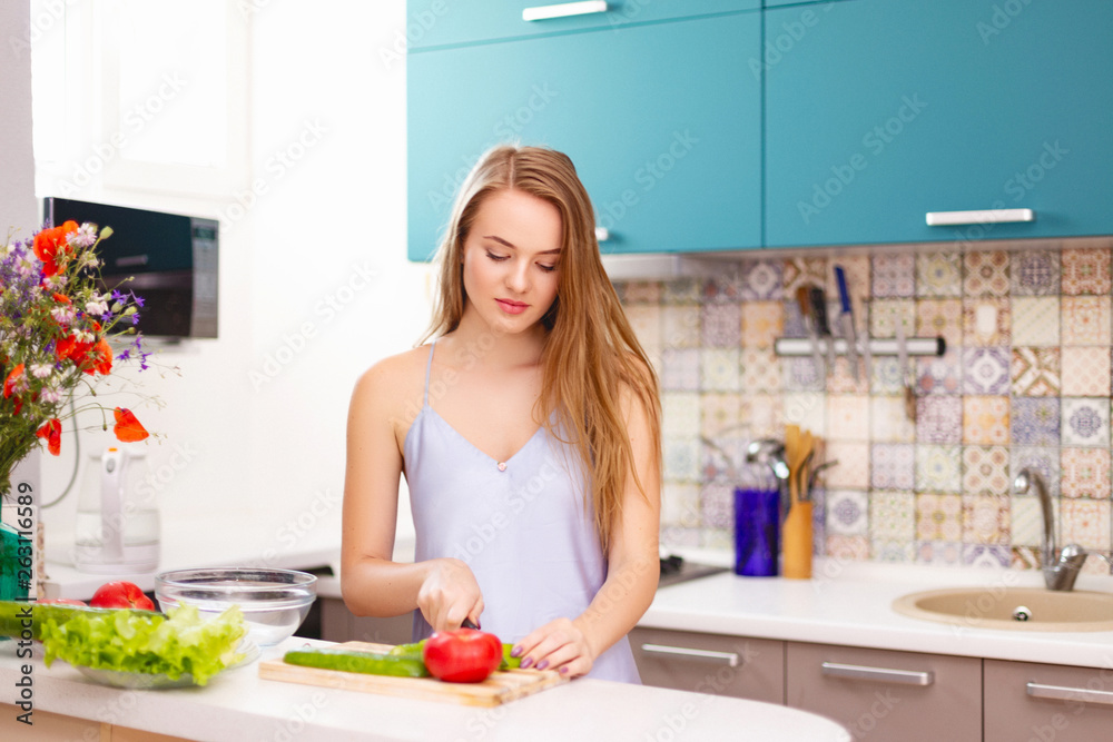 beautiful girl making salad in the kitchen