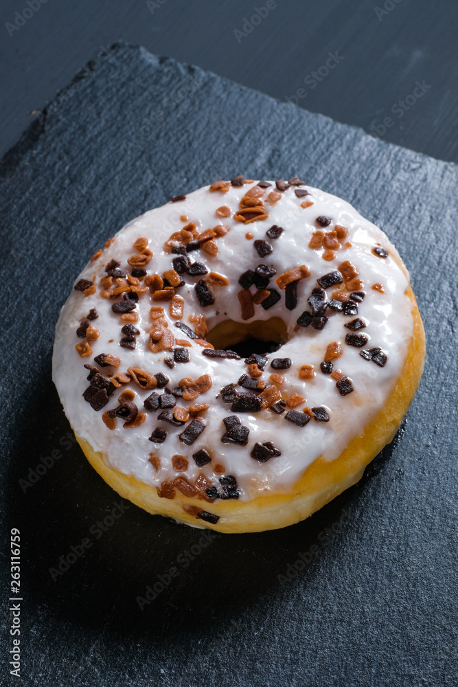 Glazed brown donut on shale dishes and black wooden background. Glazed brown donut on shale dishes and black wooden background.